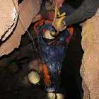 A "patient" is lowered through a narrow passage in Jewel Cave during mock rescue training.