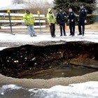 Members of Lafayette's public works and police departments look over a large sinkhole that opened Monday in Lafayette, Colorado.